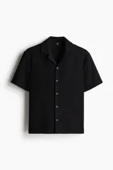 Camisa de manga corta negra con textura, cuello abierto, tapeta lisa y bajo recto.