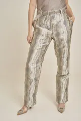 Pantalón de vestir con estampado abstracto en tonos plateados y dorados, con cinturón plateado.