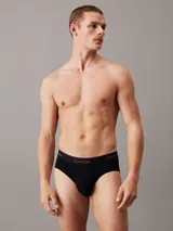 Pack de tres slips negros de algodón con cintura elástica con logo de Calvin Klein en blanco y rojo.