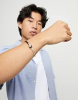 Pulsera semirígida de aleación de metales bañada en plata de ley con cuero marrón y una cuenta esférica plateada.