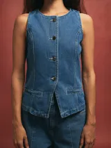 Chaleco de jean azul con botones y bolsillos frontales.
