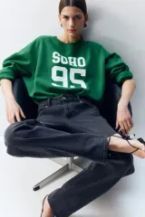 Buzo verde con cuello redondo, puños y bajo acanalados. Estampado frontal con la palabra "SOHO" y el número "95" en color blanco.