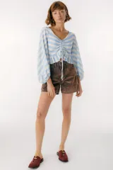 Blusa blanca de lino con escote en V, mangas largas abullonadas y frunce central.