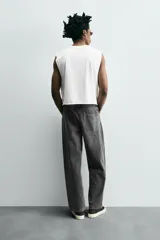 Pantalón de jean gris oscuro, corte amplio, con cinco bolsillos, efecto lavado y cierre frontal con cremallera y botón.