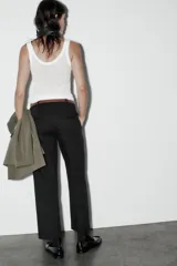 Pantalón de vestir color beige, de tiro alto y corte recto. Incluye cinturón marrón con hebilla metálica. Presenta bolsillos laterales y falsos bolsillos traseros de doble vivo. Cierre frontal con cremallera, botón interior y gancho oculto.