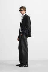 Pantalón de jean negro con efecto lavado, corte slim fit, cinco bolsillos y cierre frontal con botones.