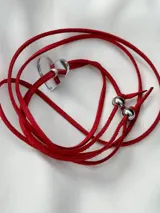 Gargantilla roja de gamuza con dije de corazón transparente y detalles metálicos plateados.