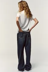 Camiseta blanca de algodón con cuello redondo y mangas cortas. Estampado frontal con texto "Meet me at Palais Lomtam, 7, Passage des Rêveries" enmarcado en un diseño ondulado.