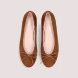 Ballerinas de gamuza color almendra, con punta redonda, ribete elástico y moño fino al tono.