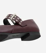 Zapatilla color borgoña de charol sintético, con puntera redonda, tira sobre el empeine con hebilla metálica plateada y taco bajo.