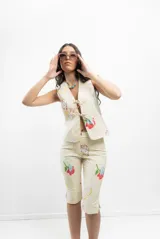Pantalón capri color crema con estampado de caras y flores, tiro medio y corte ajustado.