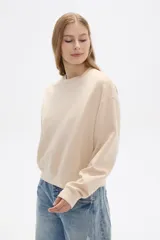 Buzo color beige de corte ancho y cuello redondo.