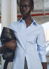 Camisa celeste de corte slim fit, con cuello camisero, cierre frontal con botones y mangas largas con puños abotonados.