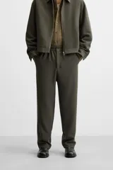 Pantalón largo color verde oscuro, de corte recto y tiro medio. Confeccionado en tejido con viscosa, con cintura elástica, bolsillos laterales y trasero de vivo. Cierre frontal con cremallera y botón.