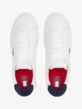 Zapatillas de estilo tenis confeccionadas en piel napa blanca, con diseño de corte bajo y cierre de cordones. Presentan un panel de contraste en el talón en color azul marino, forro de poliéster y suela de goma. Incluyen el parche distintivo de Tommy Jeans en el lateral.