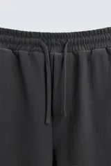 Bermuda negra de corte relaxed fit, con cintura elástica ajustable con cordón, bolsillos frontales y bolsillo trasero de parche.