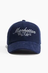Gorra azul de pana con bordado frontal de la palabra 'Manhattan' y la frase 'New York City Sport & Health Est 1991' en color blanco.