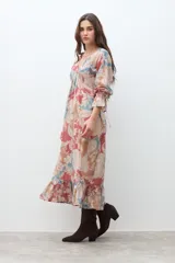 Vestido largo de manga larga, con escote en V y fruncido bajo el busto. Presenta un estampado tipo paisley en tonos rojo, azul claro y beige. El ruedo termina con un volante fruncido.