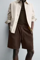 Bermuda de algodón color marrón oscuro, de corte regular fit, con cintura elástica ajustable mediante cordón. Presenta bolsillos laterales y un bolsillo trasero de vivo.