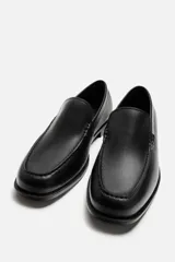 Mocasín de cuero negro con suela a tono y ligero tacón.