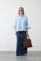 Camisa blanca de algodón con diseño utilitario y calce relajado. Presenta dos bolsillos frontales de estilo cargo con tapa y costuras a contratono.