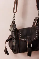 Bolso hobo pequeño de cuero color marrón oscuro con correa de hombro ajustable y removible, cierre magnético tipo solapa, bolsillos interiores con cremallera y compartimentos adicionales.