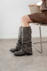 Bota de caña media color gris, con detalle de hebillas y frunces.