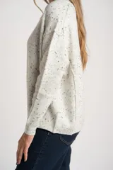 Sweater de punto color gris melange con efecto tweed o salpicado en negro, de calce oversize y cuello redondo.