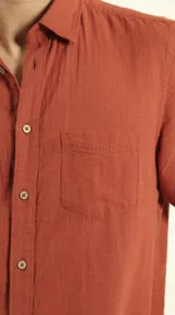 Camisa sport de manga corta color verde oliva, línea premium, con cuello clásico, cierre frontal con botones de coco y bolsillo de parche en el pecho. Confeccionada en lino y algodón.