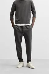 Pantalón negro de corte cropped, con cintura elástica ajustable con cordón, bolsillos laterales y traseros de vivo. El bajo tiene terminación con vuelta.
