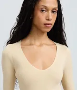 Suéter de punto color beige, con escote en V y mangas largas.