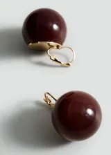 Par de aros colgantes con forma de bola color borgoña y gancho dorado.
