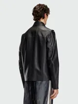 Campera de cuero negra con cuello camisero y cierre frontal. Presenta múltiples cierres metálicos en el frente, incluyendo uno diagonal en el pecho y dos bolsillos laterales.