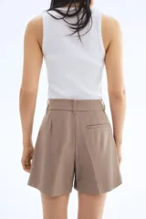 Short color beige de corte sastrero, con cierre y botón, bolsillos al bies y bolsillo trasero decorativo. Piernas con pinzas y pliegues adelante y atrás.