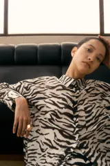 Camisa de manga larga con estampado de cebra en tonos blanco y negro. Tiene cuello clásico, cierre frontal con botones y un bolsillo de parche en el pecho.
