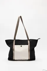 Bolso tipo tote de nylon color negro con bolsillo frontal blanco y asas largas color beige.
