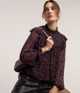 Blusa de chiffon negra con estampado floral liberty en tonos rosados, cuello alto con lastex y volados en los hombros. Mangas largas con puños ajustados.