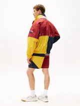 Campera de nailon con diseño color block en rojo, amarillo y azul marino. Tiene cuello alto, cierre de cremallera oculto con botones a presión, puños y bajo elásticos, dos bolsillos ribeteados en la cintura y logo de Tommy Hilfiger en la parte delantera, la trasera y las mangas.