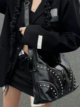 Cartera bandolera negra de cuero sintético con correa ajustable, cierre con hebilla y tachas plateadas.