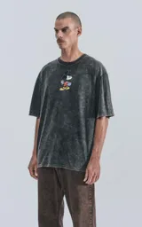 Remera de algodón premium color negro con efecto nevado (acid wash), corte oversize y cuello redondo. Presenta un estampado frontal de Mickey Mouse con una patineta.