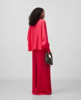 Camisa blanca de manga larga, con cuello chimenea alto y botonadura frontal oculta. El tejido es semitransparente y presenta una textura ligera.