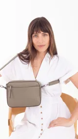 Bandolera color beige con diseño geométrico en el frente, cierre superior y correa larga regulable.