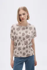 Remera blanca con estampado floral en color lila, de corte holgado y mangas cortas.