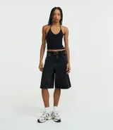 Top cropped de algodón color amarillo pálido, con escote en V pronunciado y tirantes finos que se atan en la nuca (estilo halter). El tejido es acanalado.