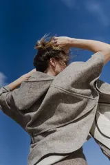 Capa amplia color marrón con capucha, cierre metálico y bolsillos delanteros. Espalda con canesú y botones laterales para generar la manga.