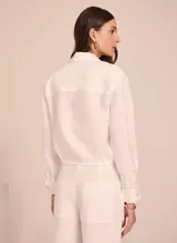 Camisa blanca de lino, de corte clásico, con cuello camisero y mangas largas con puños abotonados.