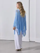 Poncho blanco de tejido calado con lurex, terminación asimétrica y cuello redondo.