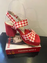 Sandalias rojas con plataforma y taco ancho. Tiras de tela con estampado de cuadros vichy rojos y blancos, y tira al tobillo con hebilla.