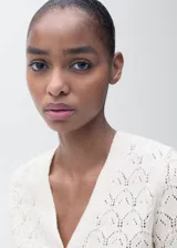 Cárdigan de punto calado color crudo, con cuello en V, cierre frontal con botones y mangas largas.