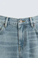 Pantalón de jean celeste, de tiro medio, corte ajustado en la parte superior y acampanado desde la rodilla. Tiene cinco bolsillos, efecto lavado y bajo irregular.